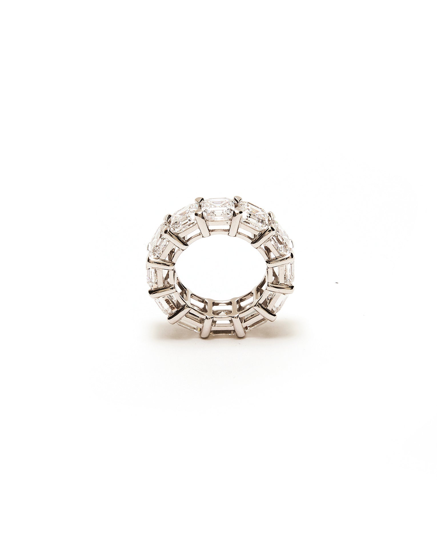 Silver ring with embedded diamond emerald stones on a white background